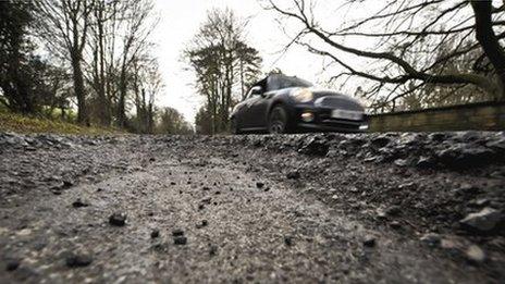 A car on a heavily potholed road in Gloucestershire