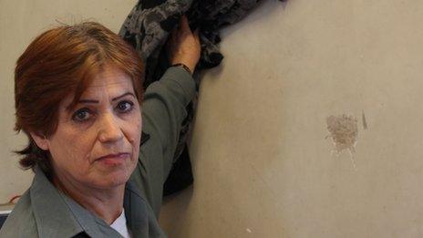 Fareeda, a prison guard shows the spot where a glass thrown at her hit the wall