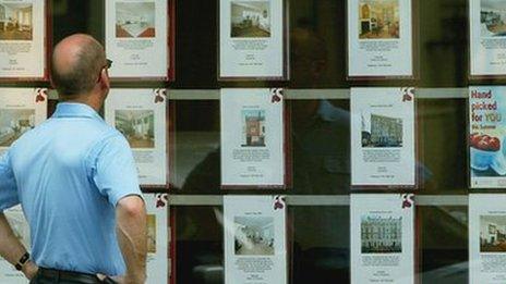 A man looks at houses in an estate agent window