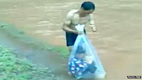 Man putting child into a bag near river