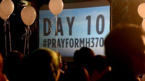 A slide projection reads "Day 10" at a rally for the missing Malaysian Airlines plane at a Kuala Lumpur area shopping mall.