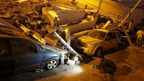 A cameraman records near cars caught under rubble after an earthquake and tsunami hit the northern port of Iquique (2 April 2014)