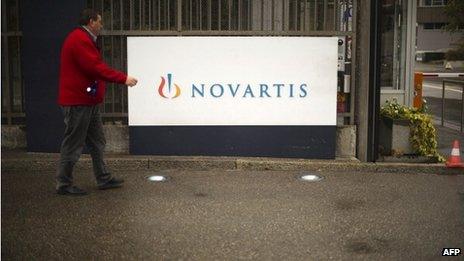 A man walking in front of a Novartis Logo