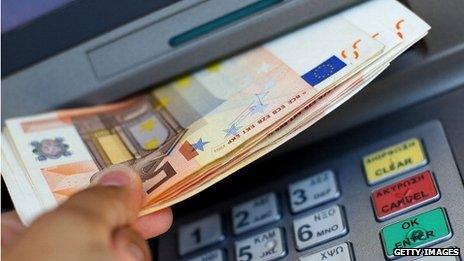A hand withdrawing euro notes from a cashpoint