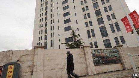 A file picture taken on February 19, 2013 shows a person walking past a 12-storey building alleged in a report by the Internet security firm Mandiant as the home of a Chinese military-led hacking group after the firm reportedly traced a host of cyberattacks to the building in Shanghai"s northern suburb of Gaoqiao.
