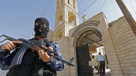 An Iraqi security officer, stands guard outside the Church of the Virgin Mary in the northern town of Bartala,