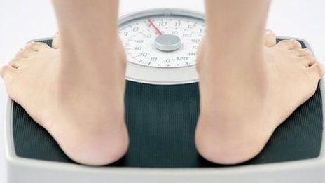 A young slim woman weighs herself on bathroom scales