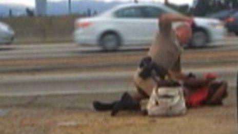 A California Highway Patrol officer straddles the woman on a Los Angeles freeway while punching her in the head