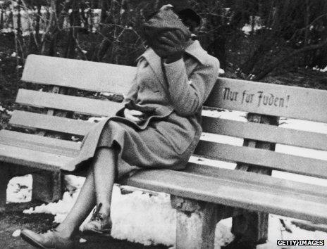 c.1938: A woman hides her face as she sits at a bench marked "Nur fur Juden", meaning "for Jews only"