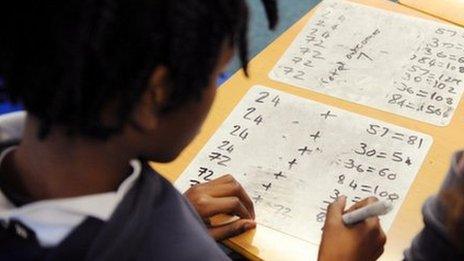 A primary school pupils works out sums in the classroom