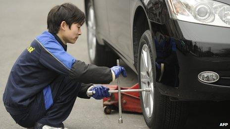 A worker at an auto shop changes the tyres on a car in Shanghai