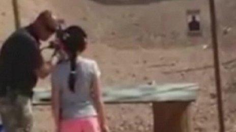 Instructor at Last Stop firing range showing nine-year-old girl how to fire Uzi