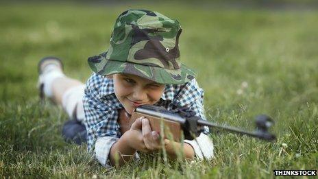 A young boy holds a rifle