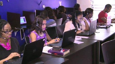 Young Jobberman employees sitting in front of computers wearing headsets.