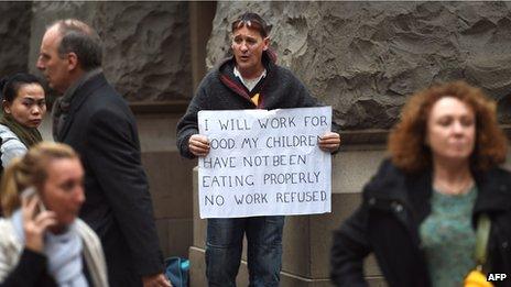 An unemployed man holding a sign offering to work for food for his children as Australia's unemployment rate spiked to a 12-year high of 6.4 percent in July