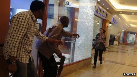Armed police guide a woman carrying a child to safety during the Westgate attack
