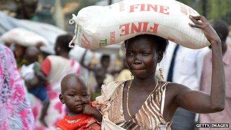 A woman with a child carrying a sack of rice