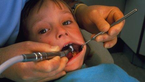 Child at dentist having tooth drilled to treat tooth decay