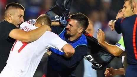 Serbia's Stefan Mitrovic is surrounded as he tries to pull down the Albanian flag