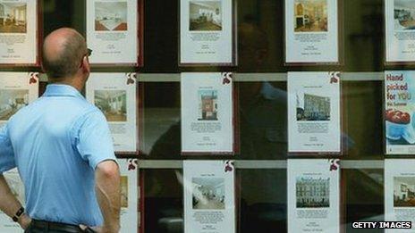 A man looks at houses in an estate agent window