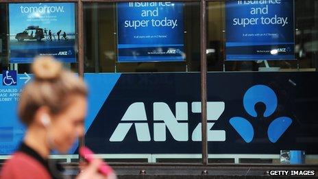 A woman walks past Australia and New Zealand Banking Group (ANZ) signage displayed