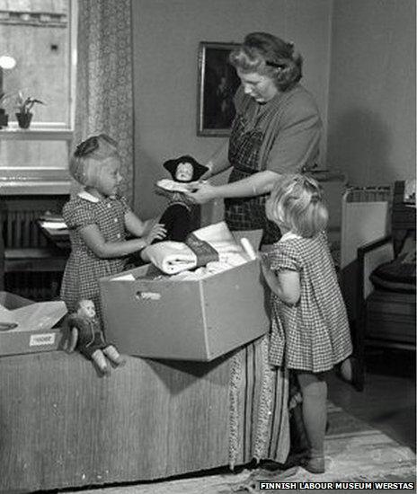 Mother and daughters look at a pack from 1947