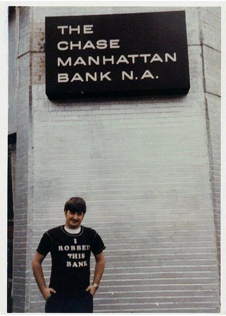 Wojtowicz poses in a T-shirt that says 'I robbed this bank' - in front of the bank