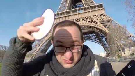 A man placing a kippah on his head beside the Eiffel Tower