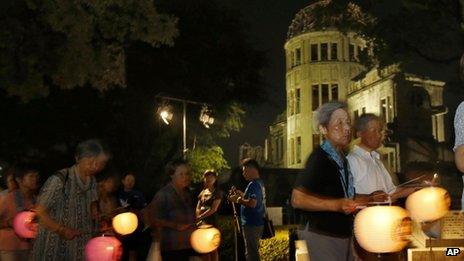 Буддийские последователи держат бумажные фонарики, маршируя в молитве за мир вокруг освещенного Купола атомной бомбы в Хиросиме, западная Япония, понедельник, 5 августа 2013 г.
