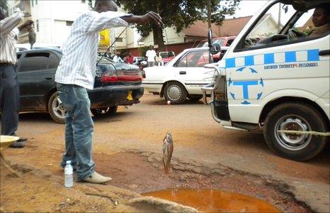 Ugandan protesters fish in potholes in the Ugandan capital, Kampala