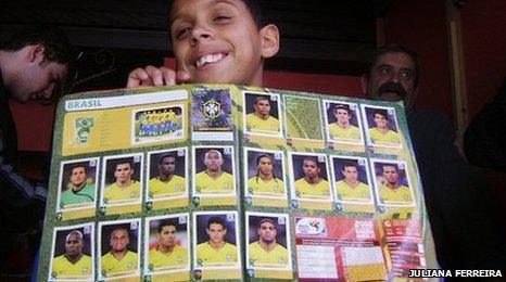 Boy holds an album he has bought and filled with the Brazilian team stickers