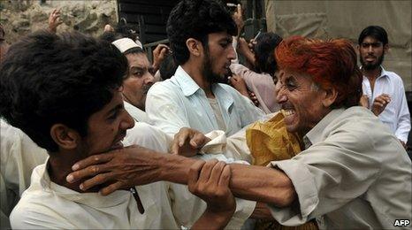 Pakistani flood victims fight for relief bags distributed by soldiers in Nowshera on 20 August 2010