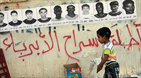 Posters of detainees with graffiti, "free the innocent people" on the streets of Malkiya village, Bahrain