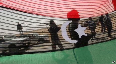 Rebels seen through a pre-Gaddafi flag outside al-Agila, Libya. 30 March 2011