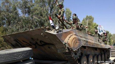 Syrian troops on a tank that says 'The soldiers of Assad'