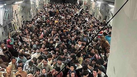 The inside of a military cargo plane with hundreds of people crammed inside