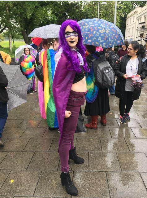 A Pride festival-goer in a purple superhero outfit