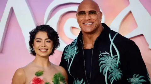 Getty Images US actress Auli'i Cravalho (L) and US actor Dwayne Johnson pose on the red carpet upon arrival for the UK Premier of "Moana 2", at the Cineworld, in Leicester Square, in central London, on November 24, 2024.