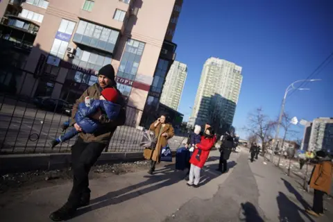 Anadolu Agency / Getty Images People evacuate the area after an attack on a residential building during Russia's military intervention in Kyiv, Ukraine on February 26, 2022.