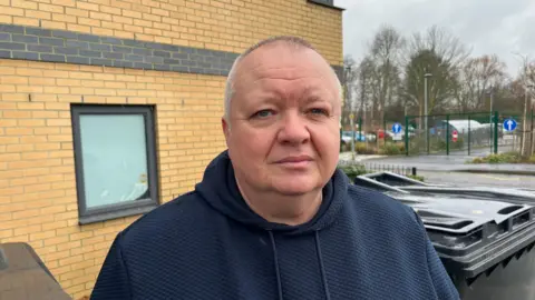 Richard Strangward, a man with short white hair. He is wearing a blue hoodie and looking into the camera.
