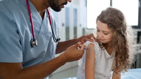 A doctor vaccinating a young girl.