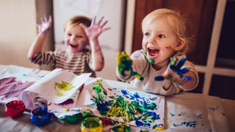Getty Images Children painting on kitchen table