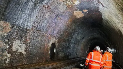 Network Rail Blackheath tunnel inspected by three men in orange jacket