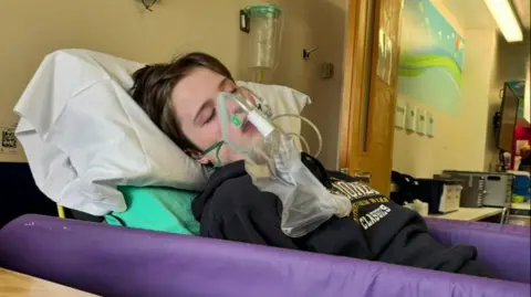 Provided Isla asleep in a hospital bed with an oxygen mask.