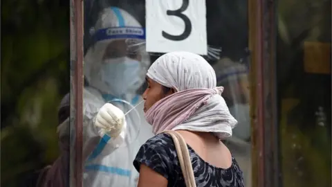 Getty Images A health worker collects a swab sample from a woman for Covid-19 rapid antigen test in New Delhi, India