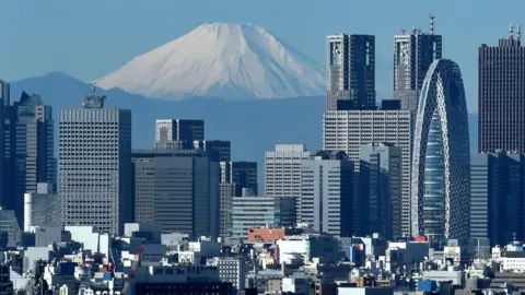 AFP Japan's highest mountain, Mount Fuji (C) is seen behind the skyline of the Shinjuku area of Tokyo on December 6, 2014.