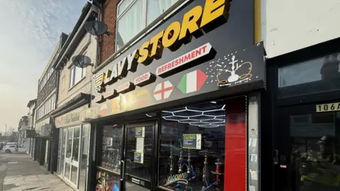 Wiltshire Police The outside of a shop in Swindon. The storefront is black and features several flags. The logo - Lavy Store - is written in white and yellow capital letters. There is a sign in the window to say the premises is closed. 