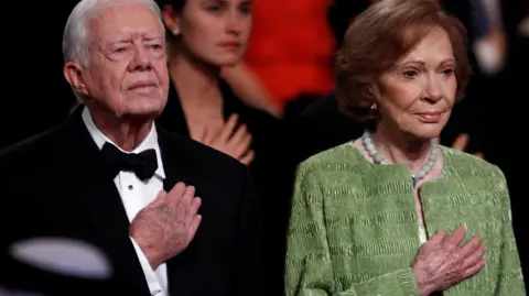 Reuters Former U.S. President Jimmy Carter and his wife Rosalynn hold their right hands on their chests at a ceremony