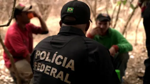 An officer from Brazil's federal police interviews two carnauba workers