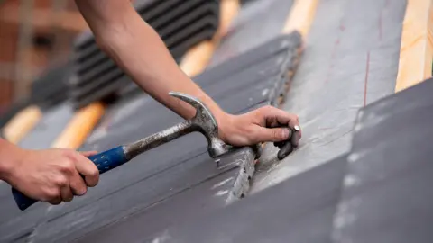 Getty Images Stock image of person fixing a roof with hammer